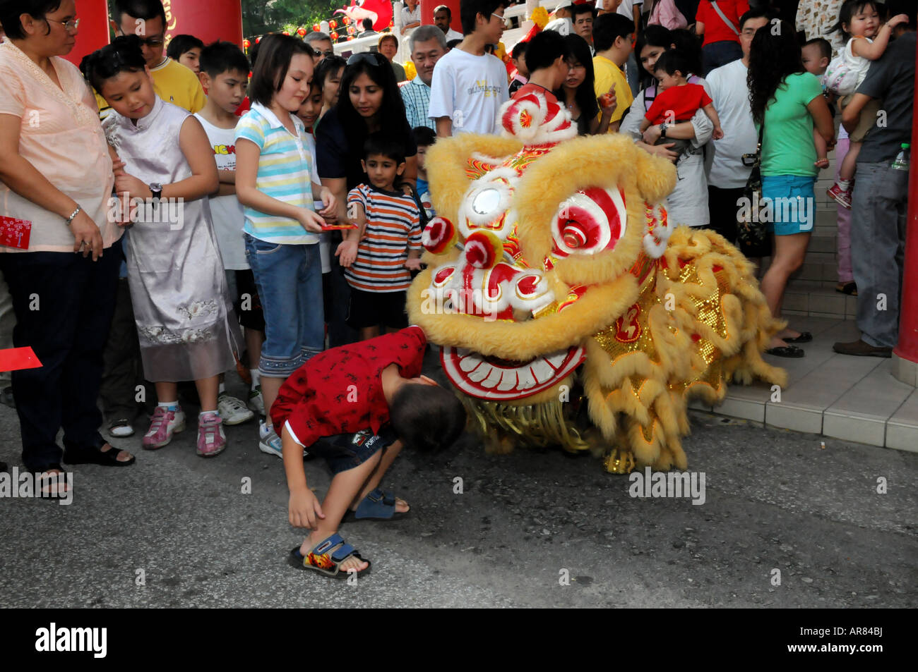 Ein Kind peeping durch den Mund des Löwes während einer Löwe-Tanz-Performance während Chinese New Year in Malaysia Stockfoto