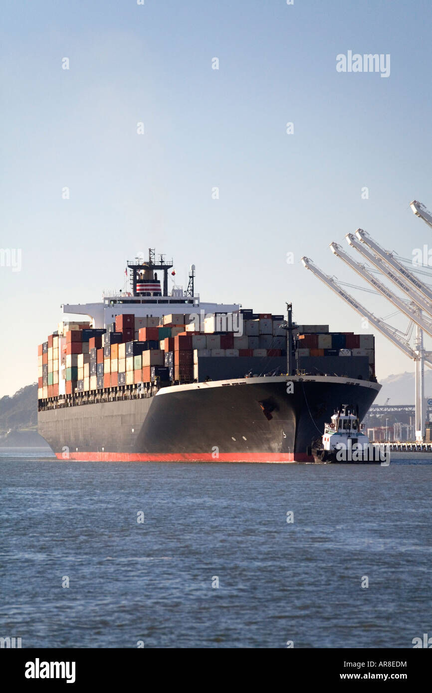 Ein Schlepper hilft ein großes Containerschiff Hafen von Oakland geben Sie auf dem Weg von China zu den Docks der USA. Stockfoto
