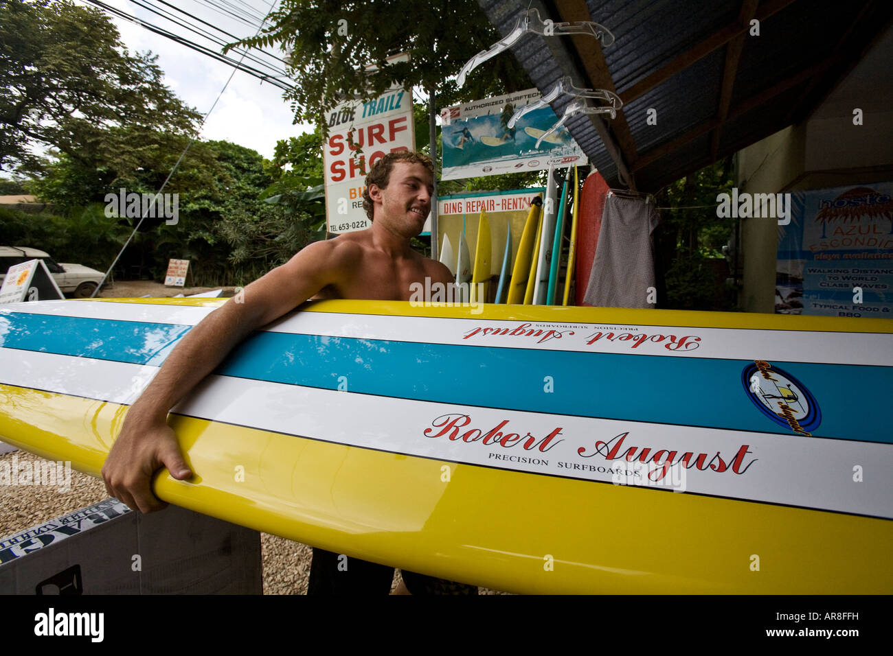 Ein Surfer trägt ein Surfbrett von Robert August in einen Surfladen in Tamarindo, Guanacaste, Costa Rica Stockfoto