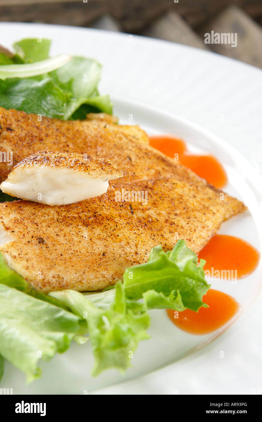 Erfahrene flockige Weißfisch auf einem grünen Salat mit Orangensauce Stockfoto