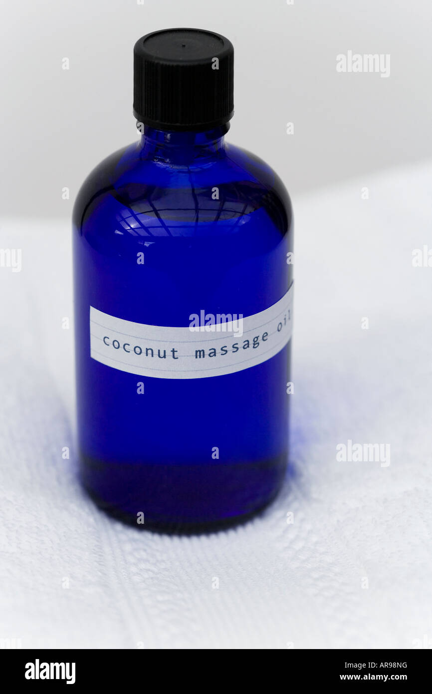 Kokos Massageöl in einer blauen Glasflasche erschossen auf einem weißen Baumwolltuch Stockfoto