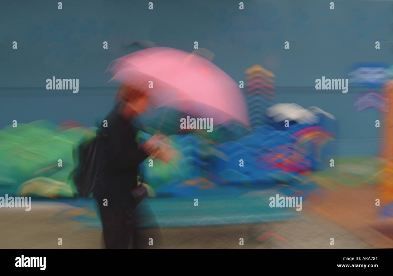 Frau, die im Regen mit rosa Regenschirm läuft Stockfoto