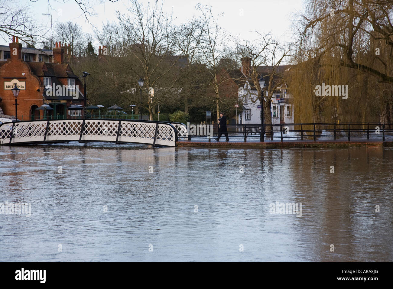 Ein Geschäftsmann bereitet sich auf eine Brücke über die überfluteten Fluss Wey in Guildford, Surrey, England. Stockfoto