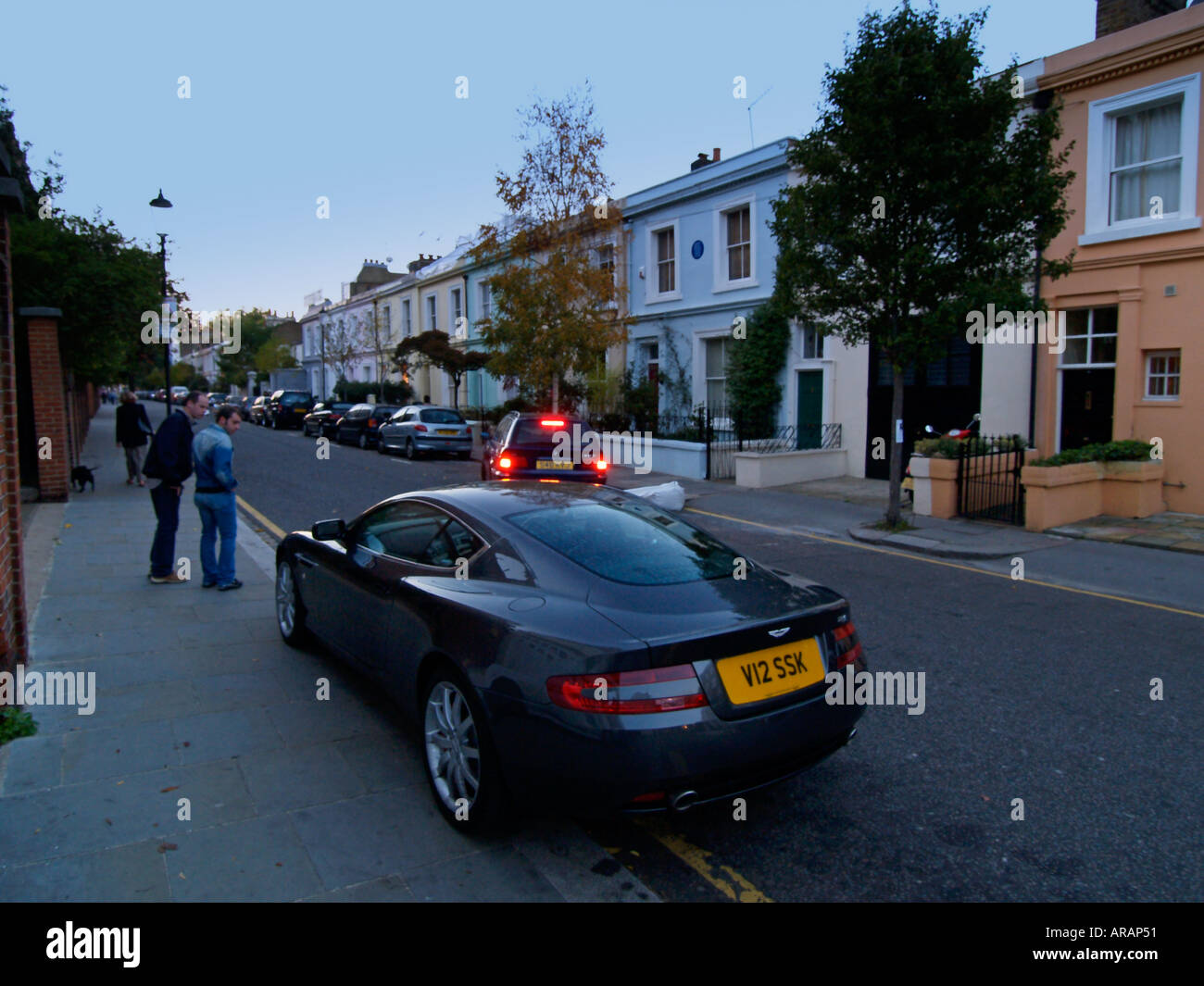 Zwei junge Männer bewundern einen Aston Martin DB9 Sportwagen in der Abenddämmerung auf der Portobello Road London UK Stockfoto