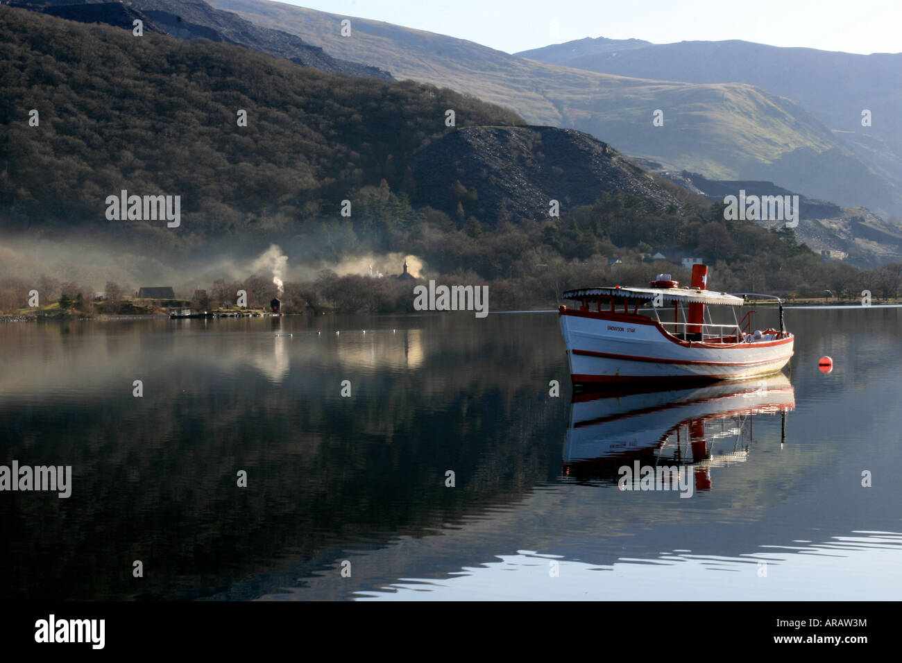 Ein Boot liegt auf dem ruhigen See im frühen Morgenlicht in Llanberis, Nordwales. Stockfoto