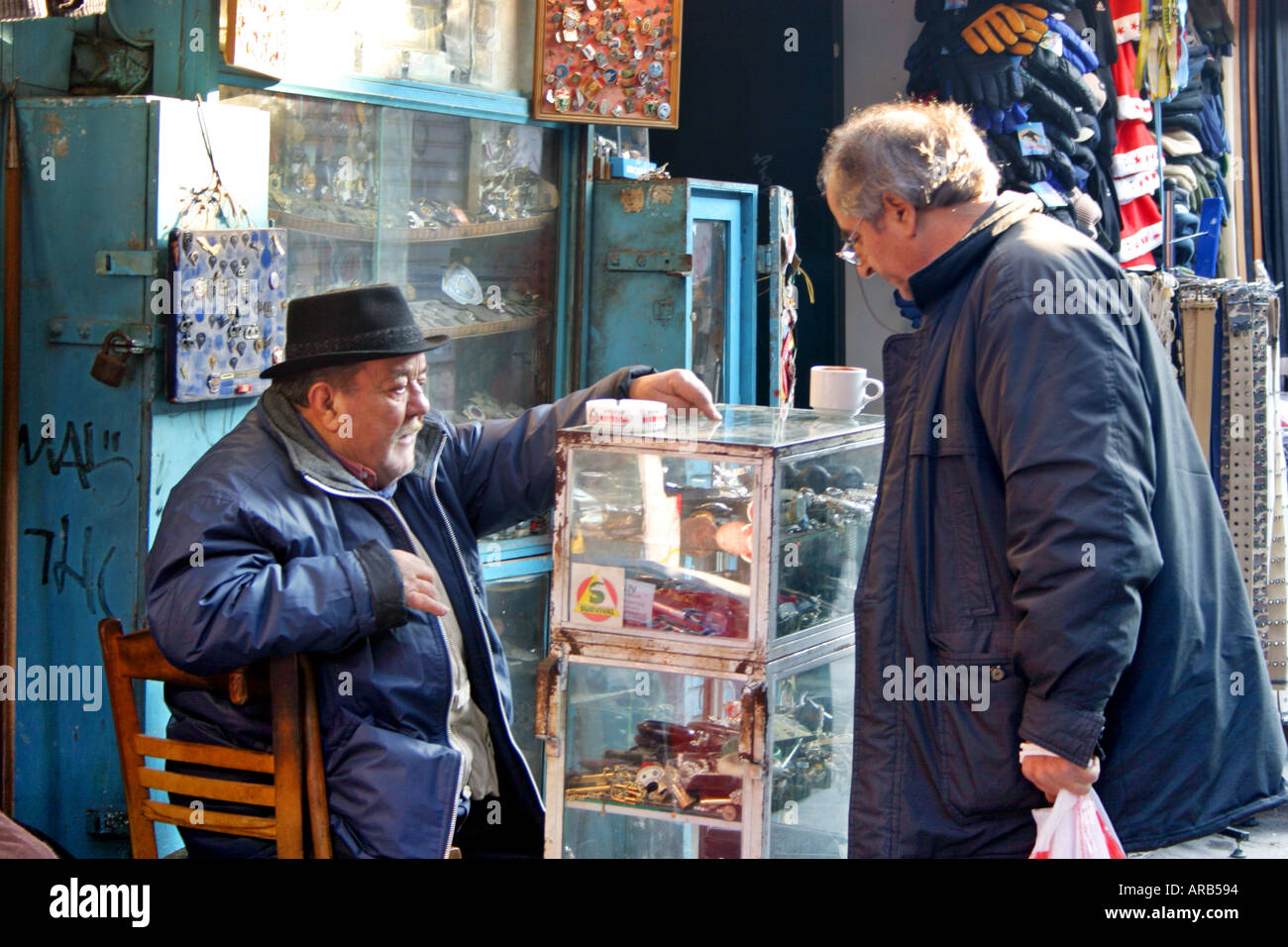 Bypasser einkaufen verwendet Münzen und/oder Kunstobjekte im Shop im Plaka Viertel Fußgängerzone Athen Griechenland Winter Sunshine Kaufmann Stockfoto