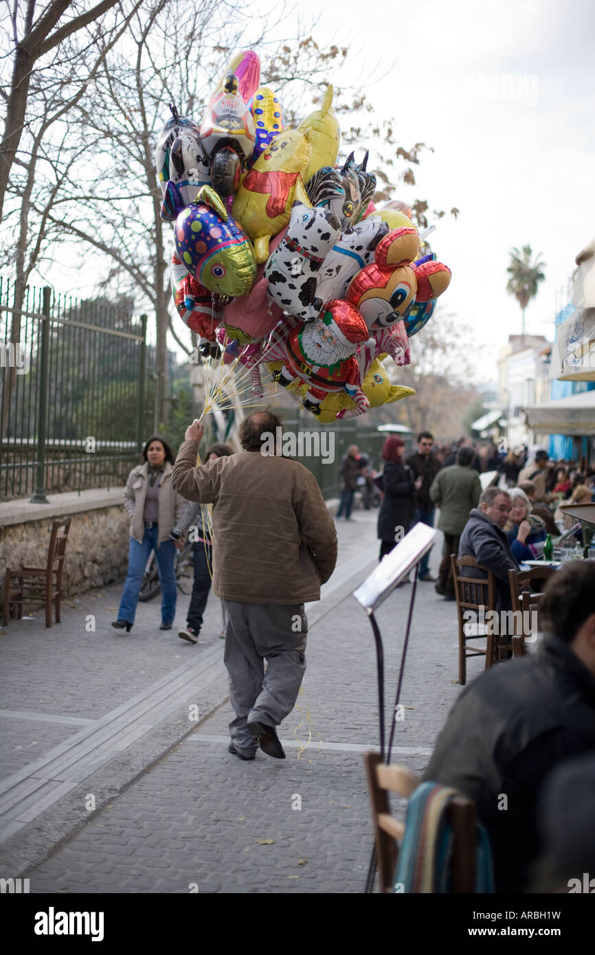 Mann zu Fuß mit Luftballons durch einen überfüllten Gasse Stockfoto