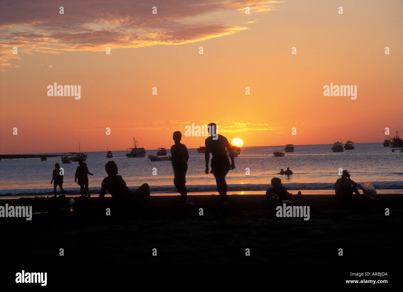 Sonnenuntergang am Sandstrand mit Angeln Boote Schwimmer an San Juan del Sur Pazifikküste Nicaragua Stockfoto