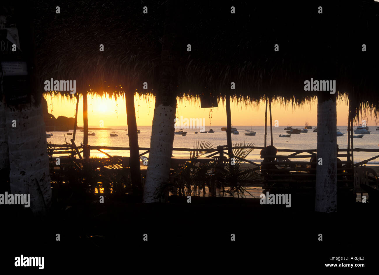 Sonnenuntergang über dem Meer mit Booten von Strandrestaurant mit Stroh Dach San Juan del Sur Pazifikküste Nicaragua verankert Stockfoto