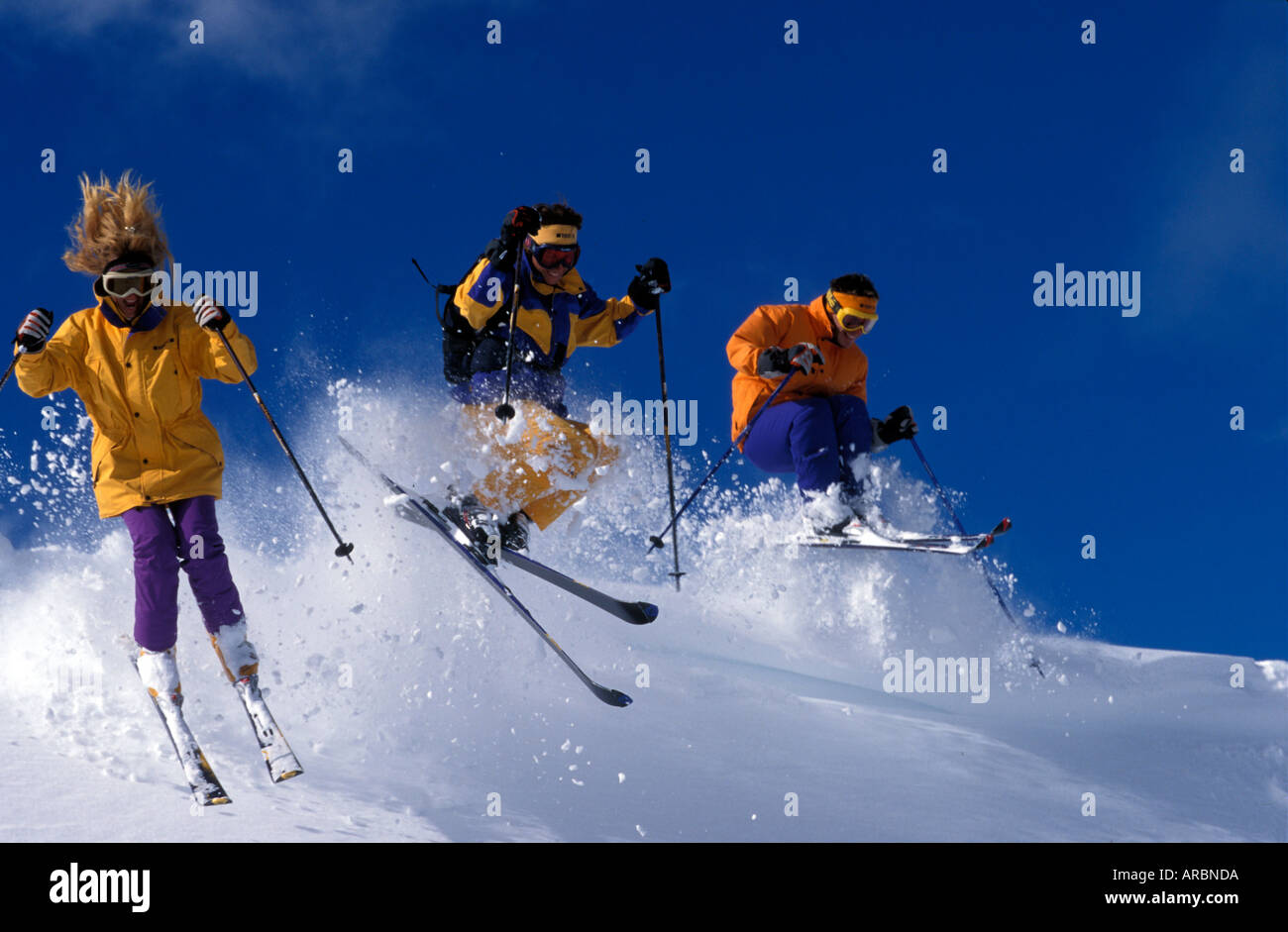 Gruppe von drei Skifahrer geht mit Geschwindigkeit über einen Hügel im Tiefschnee Stockfoto