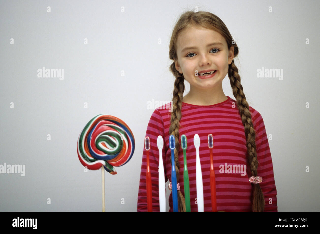 Lächelnde Mädchen vor Zahnbürsten und Lolly Stockfoto