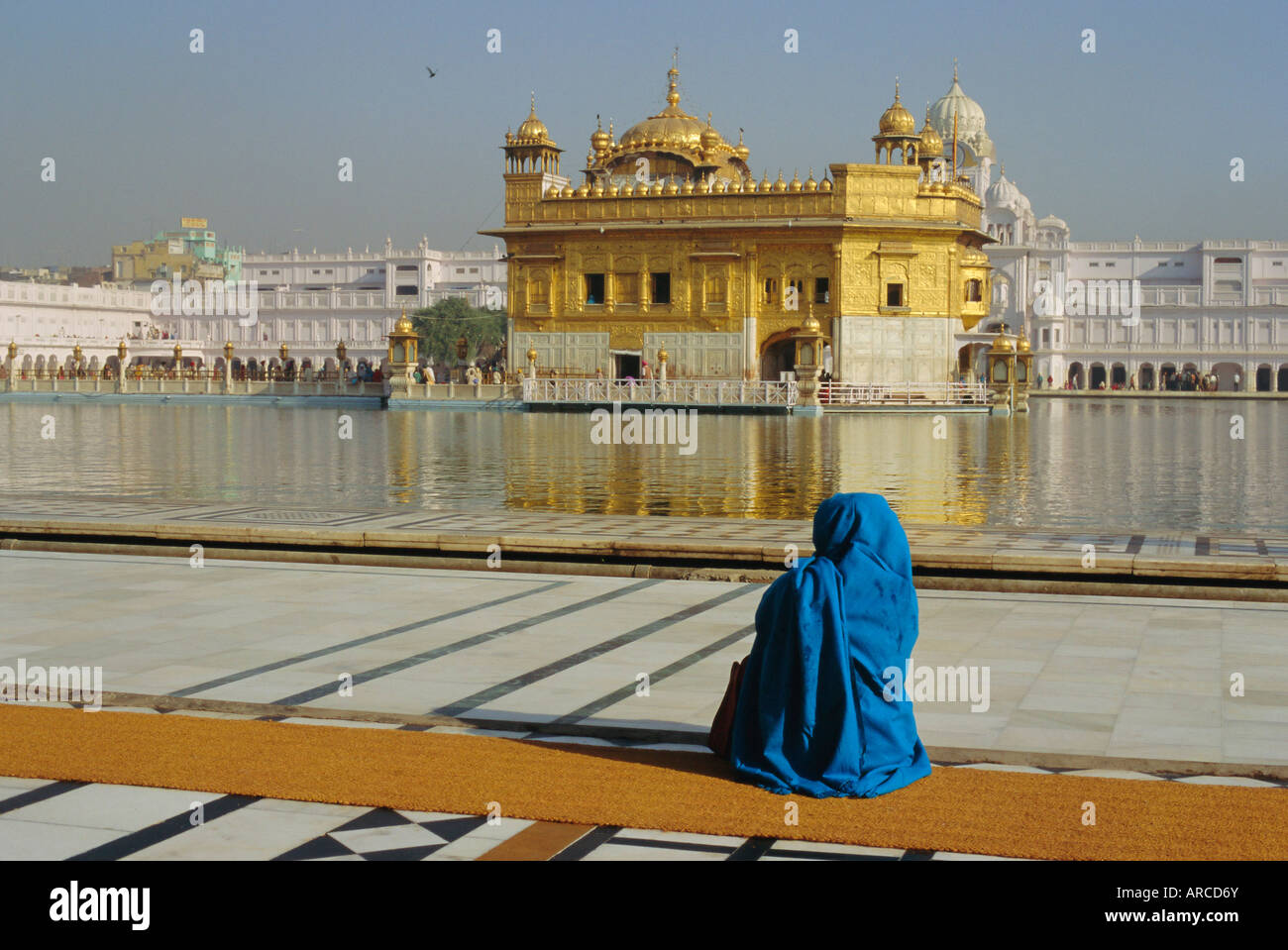 Ein Pilger in blau sitzt durch den Heiligen Pool Nektar auf den goldenen Tempel, Zentrum der Sikh Religion, Amritsar, Punjab, Indien Stockfoto