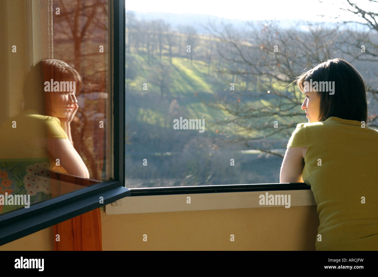 Junge Frau, Blick aus dem Fenster auf einen Blick auf die Landschaft - spiegelt sich in dem Glas, Rückansicht Stockfoto