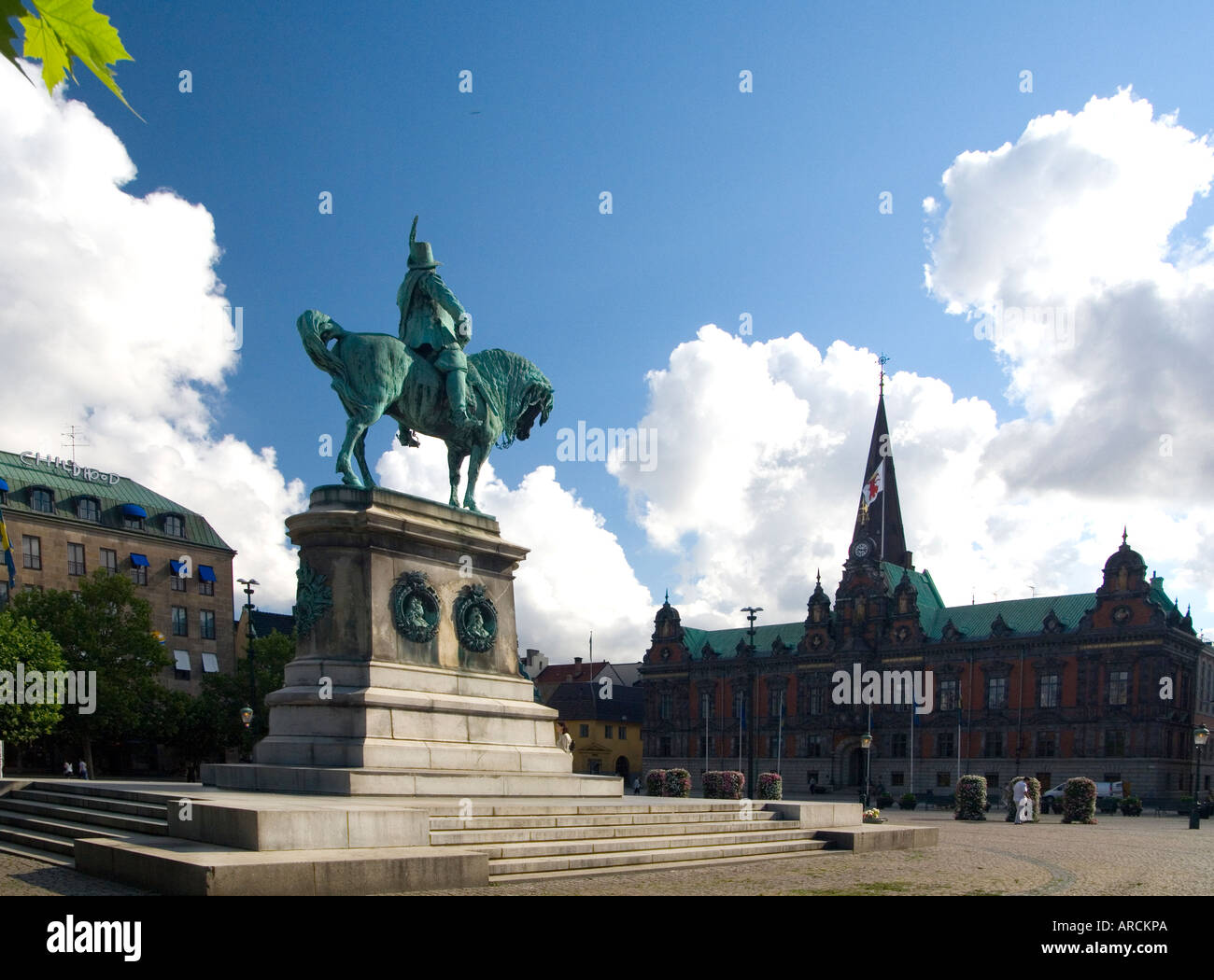 Die Statue von König Karl X auf dem Platz namens Stortorget in Malmö Schweden mit dem Rathaus und der Turm der St. Peterskirche Stockfoto