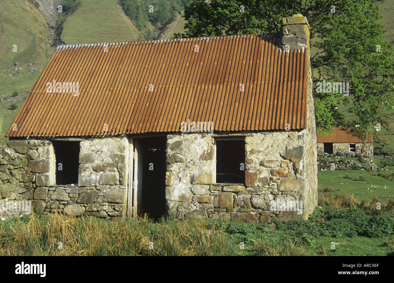 Stone Cottage mit rostigen Wellblechdach Stockfoto