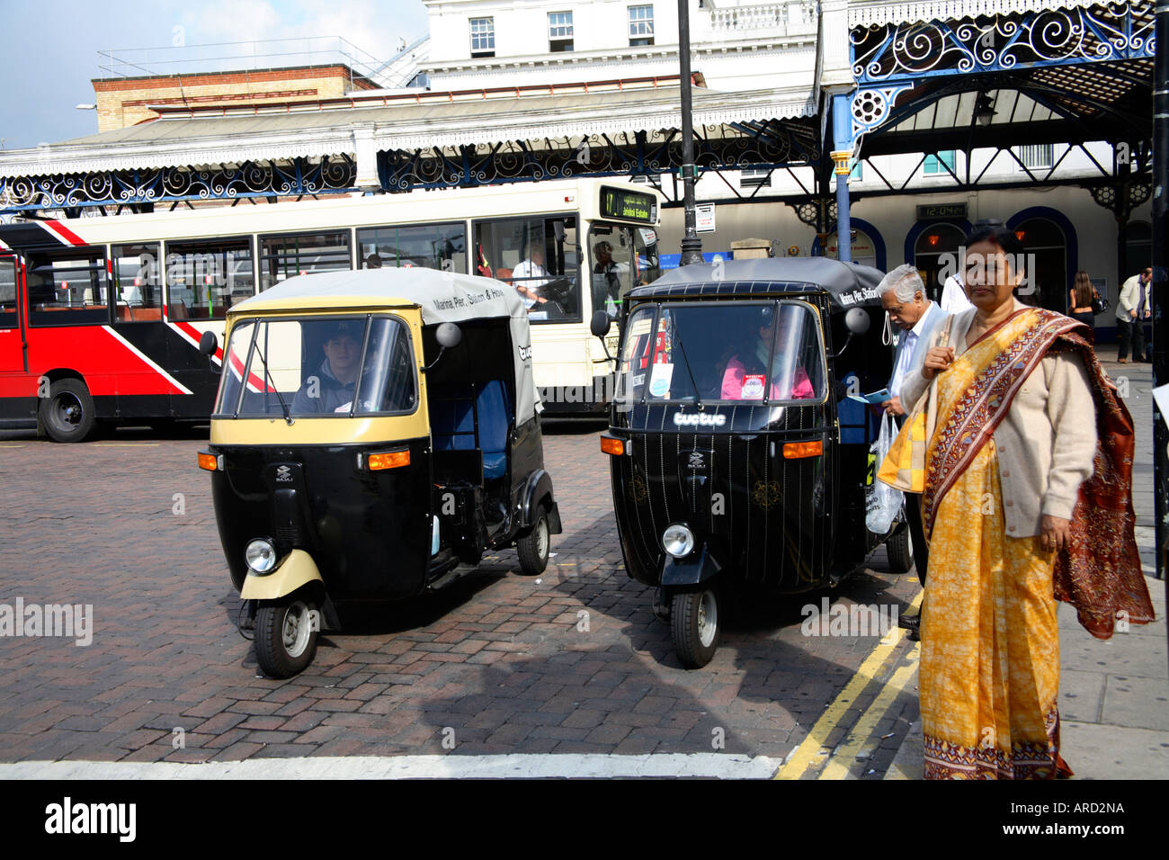 Indisches Paar mit TucTuc/Tuk Tuk/Auto Rickshaw vor dem Bahnhof Brighton, Großbritannien Stockfoto