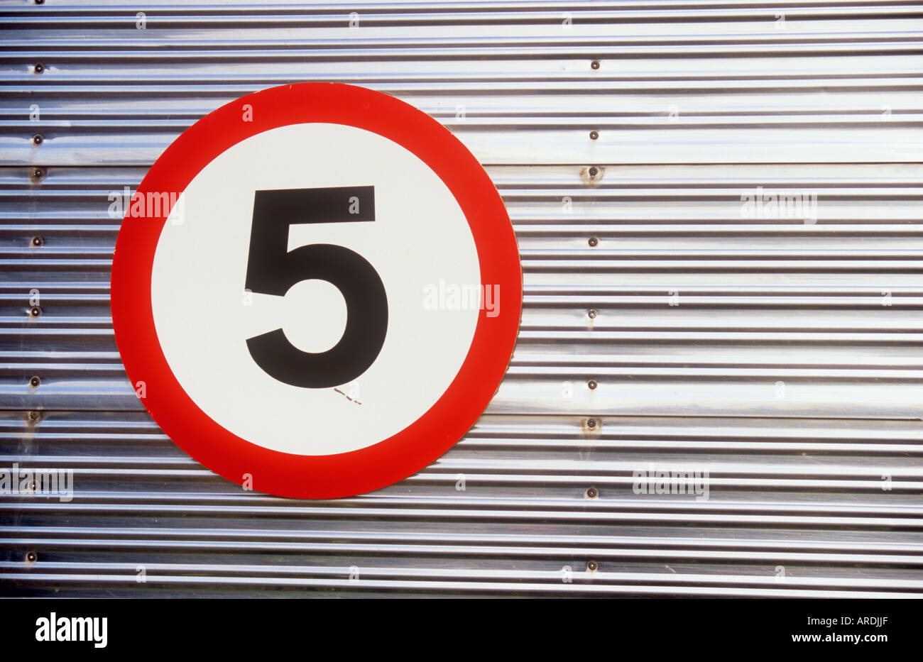 Detail der silberne reflektierende Aluminium Zaun oder Rollo mit roten und weißen Scheibe Schild schwarz 5 im Zentrum Stockfoto