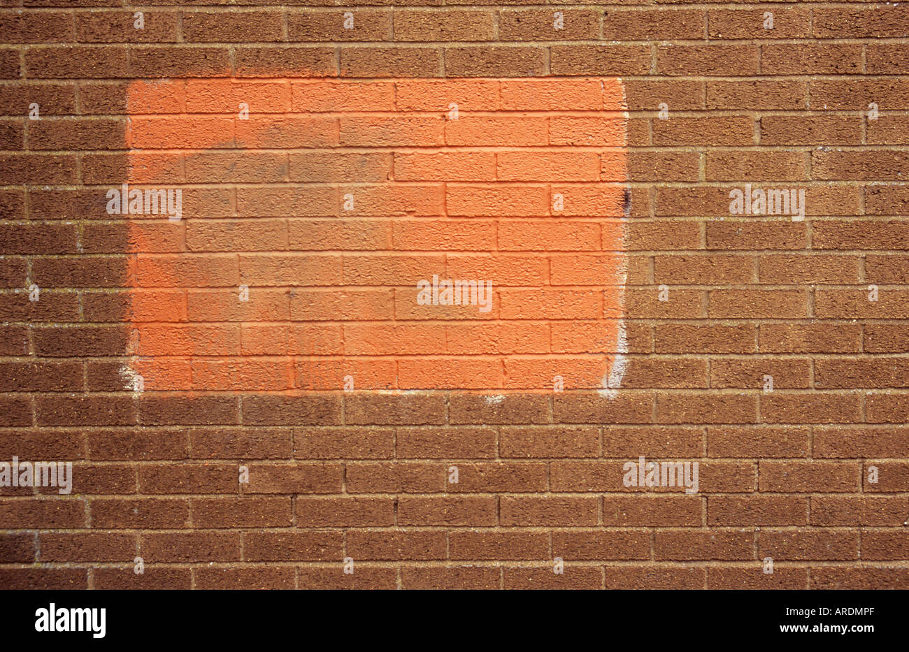 Teil eine strukturlose hässliche Mauer mit einem Patch von nicht übereinstimmenden roter Farbe Graffiti zu verschleiern versucht Stockfoto