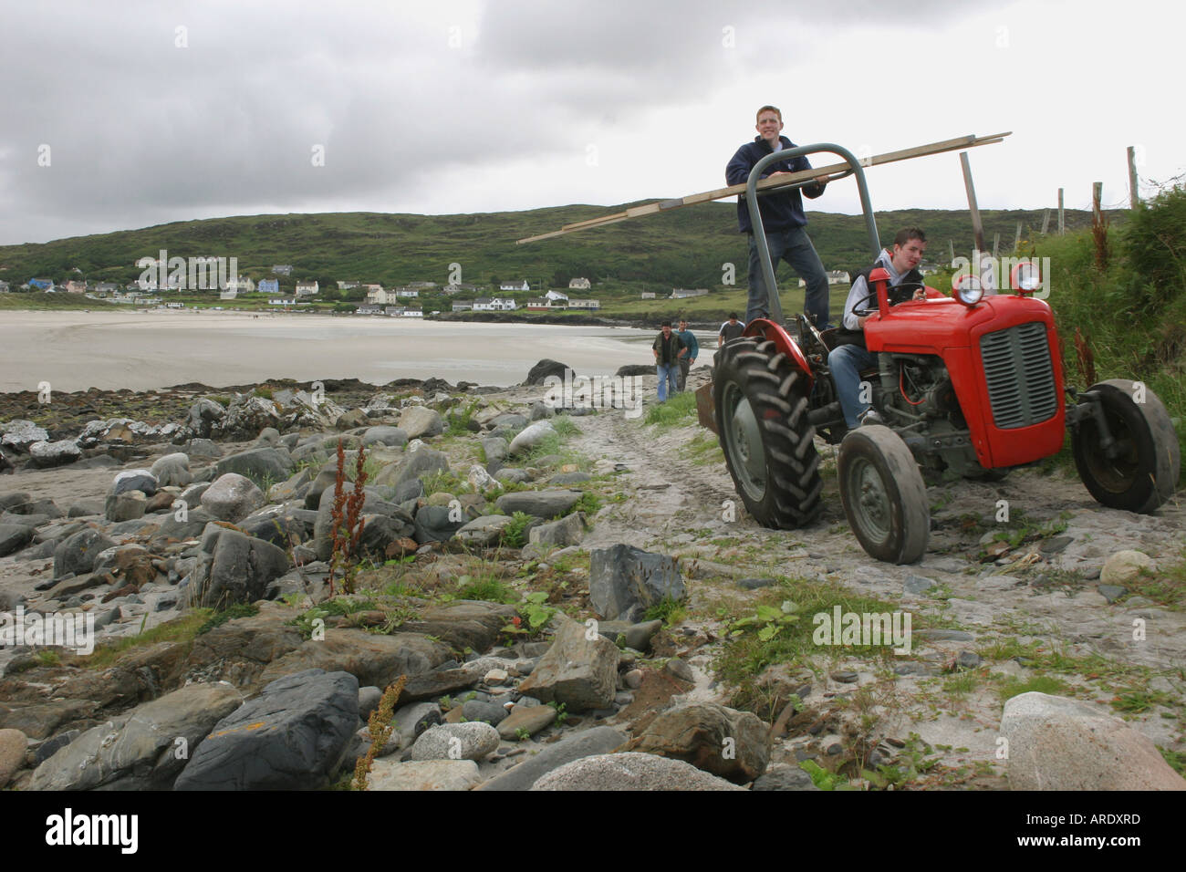 zwei junge Männer auf einem roten Traktor auf Inishkeel Island, County Donegal, Irland Stockfoto