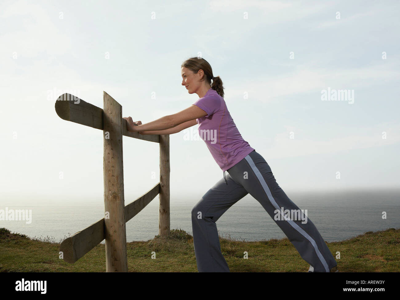 Eine Frau erstreckt sich auf einer Land-Zaun Stockfoto