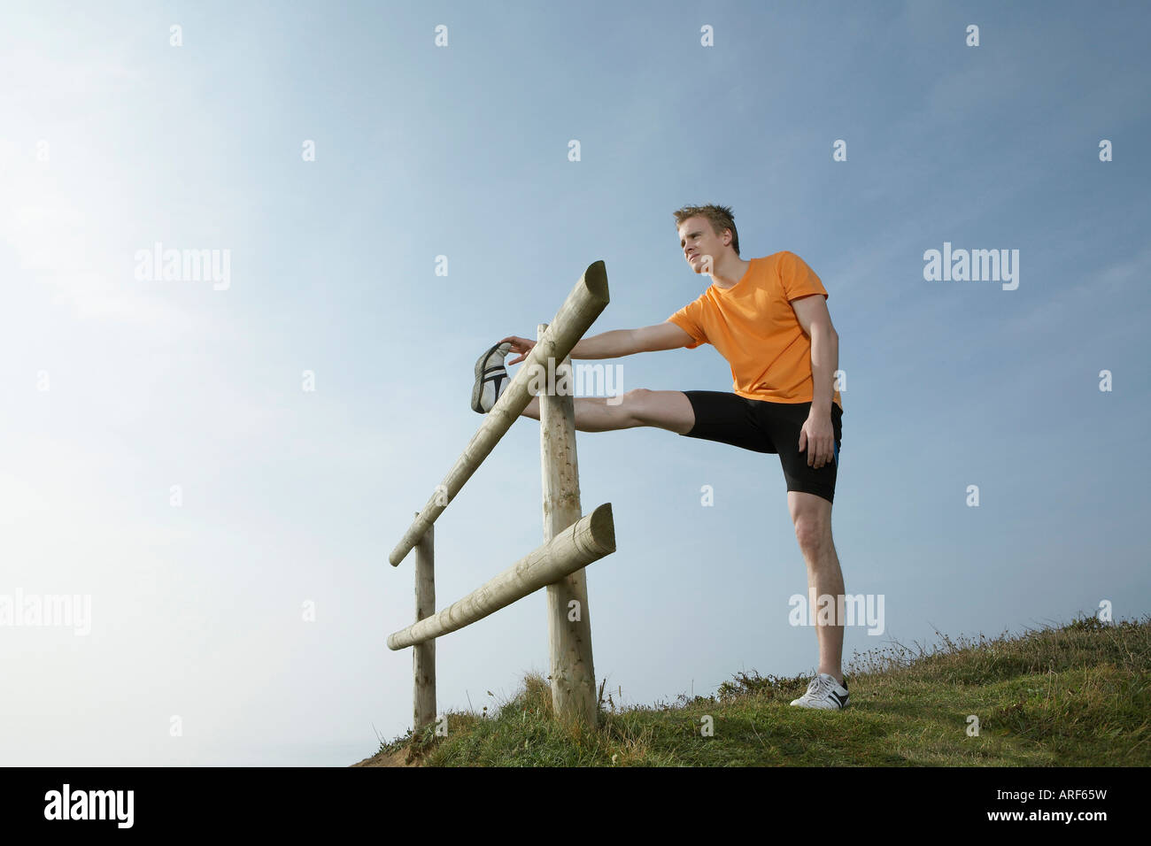 Ein Mann erstreckt sich auf einer Land-Zaun Stockfoto