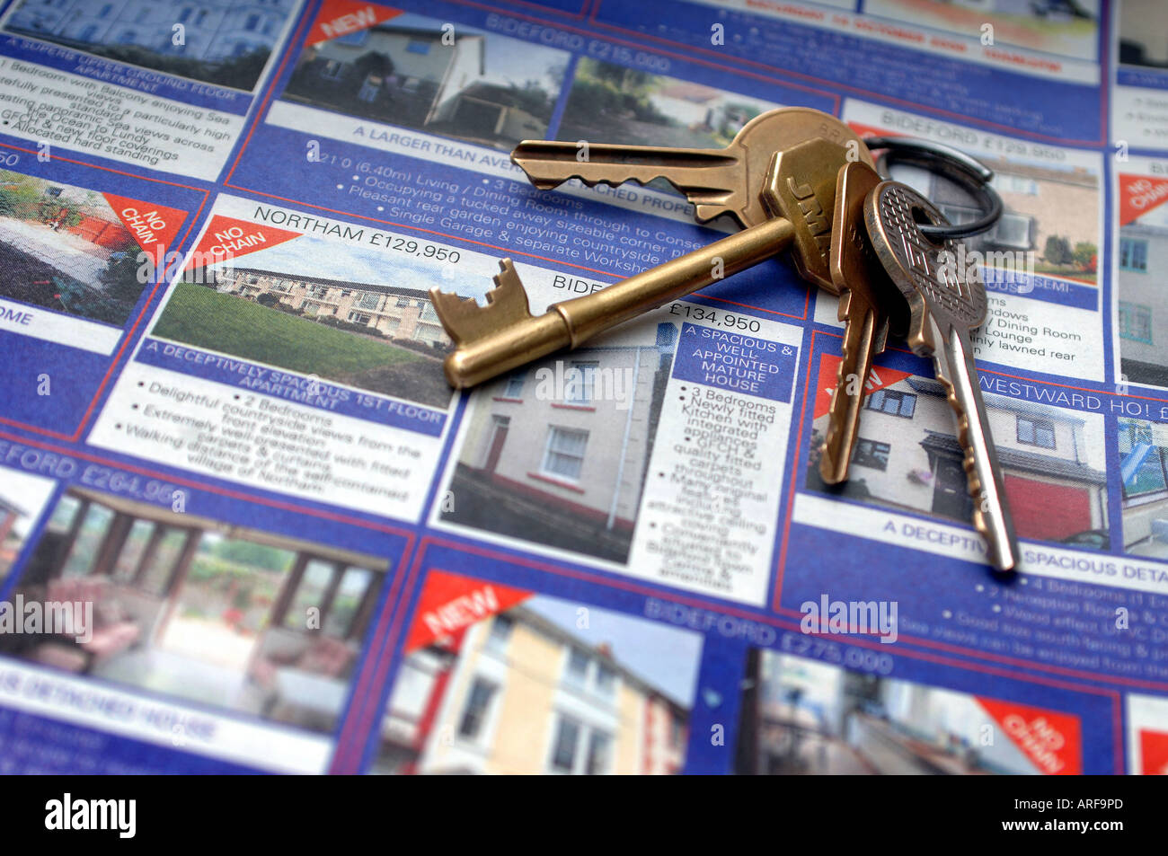 Hausschlüssel liegen oben auf Werbung für Häuser zum Verkauf in einer Zeitung. Stockfoto