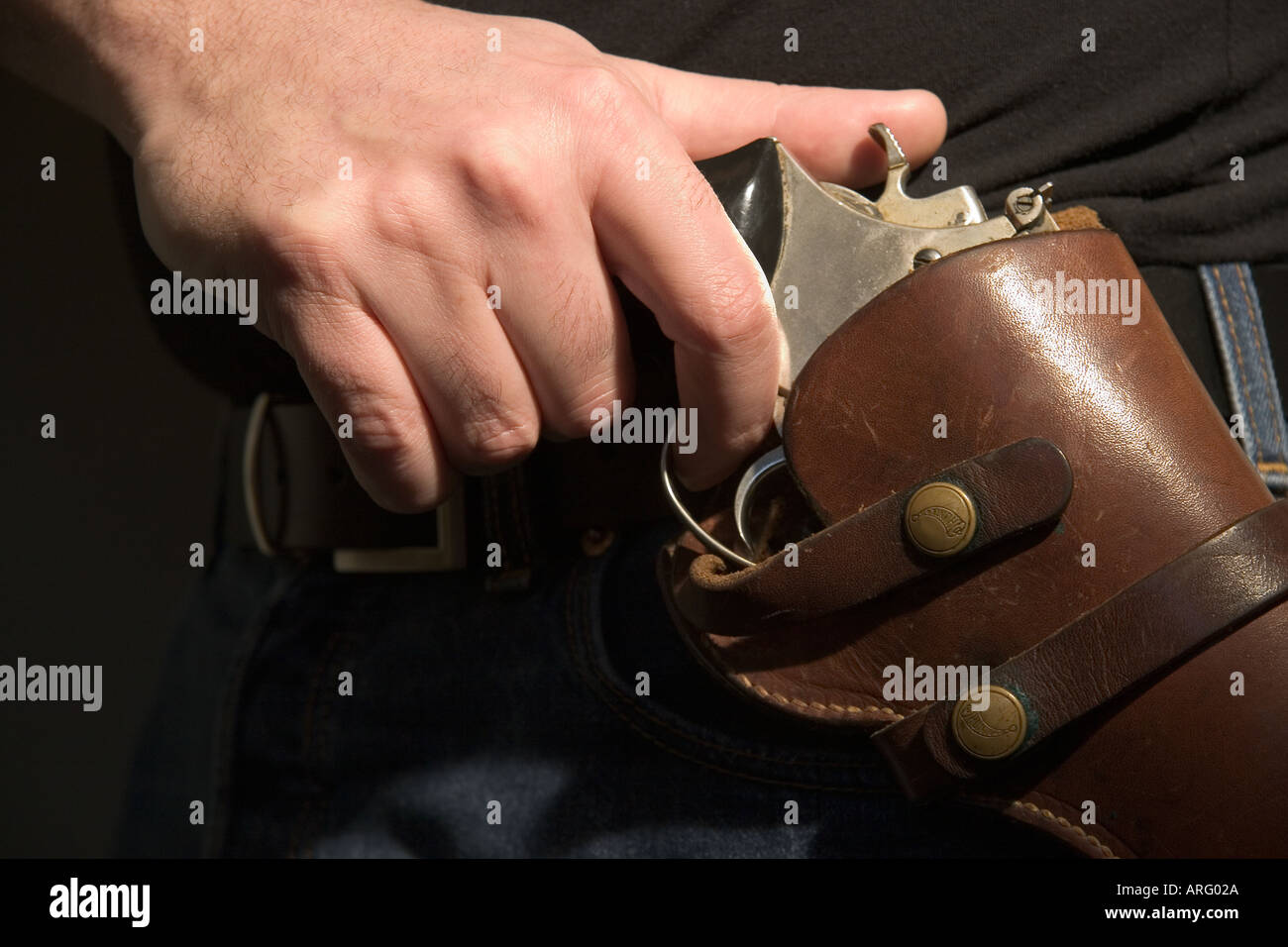 Mans Handzeichnung eine 44 Magnum Pistole aus einem Lederholster auf Taille Person trägt Jeans und ein schwarzes t Shirt Modell veröffentlicht Stockfoto