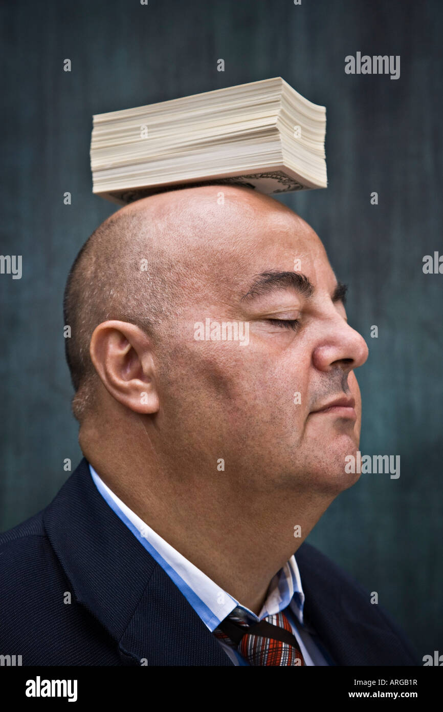 Geschäftsmann mit Stapeln von Bargeld auf Kopf Stockfoto