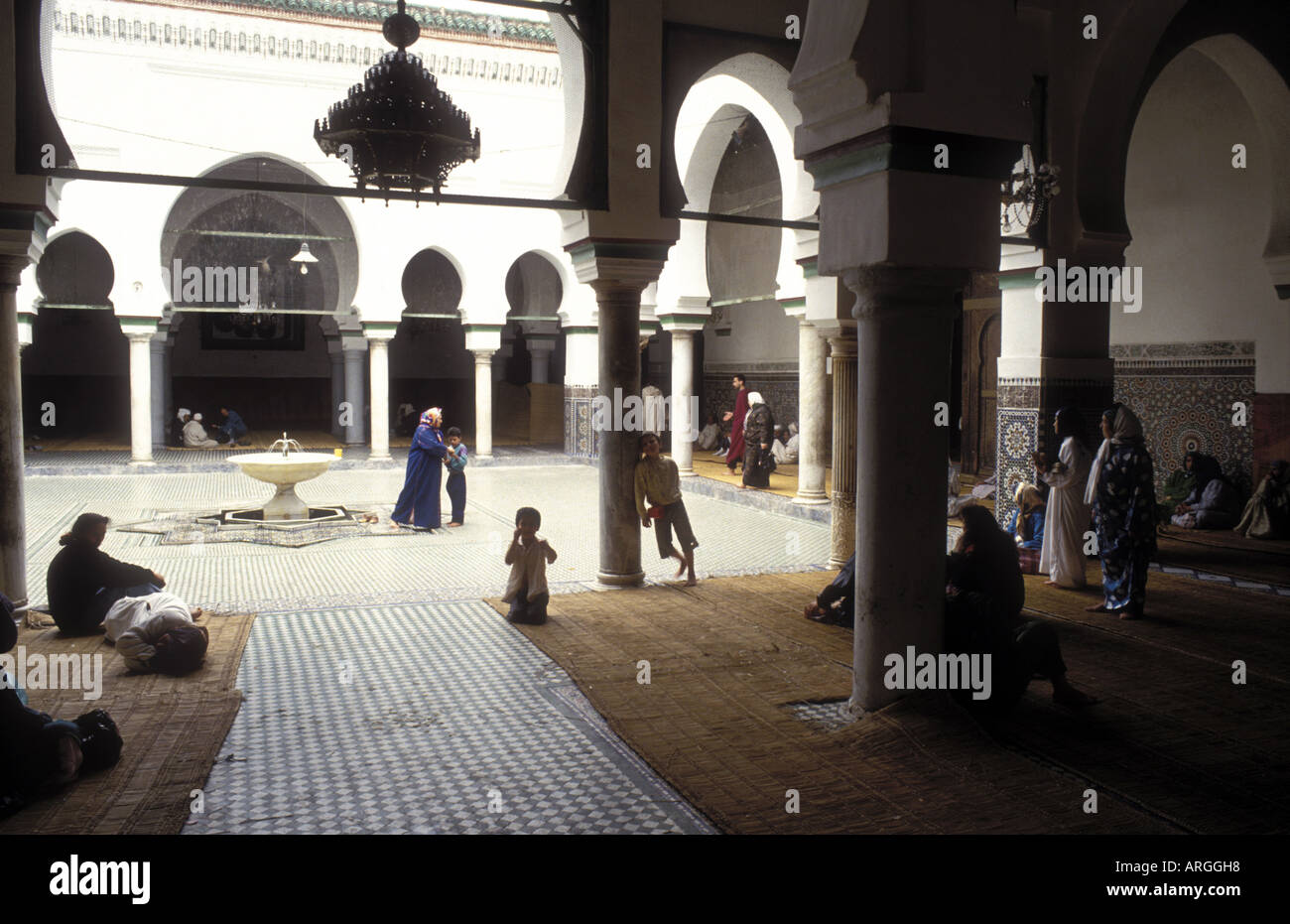 Lokalen muslimische Familien versammelten sich im Schatten der Arkadenhof und rund um den zentralen Brunnen der Zaouia Moulay Idriss II gebaut im Jahre 1437 in Fes es Bali Ortsteil der Stadt Fes Stockfoto