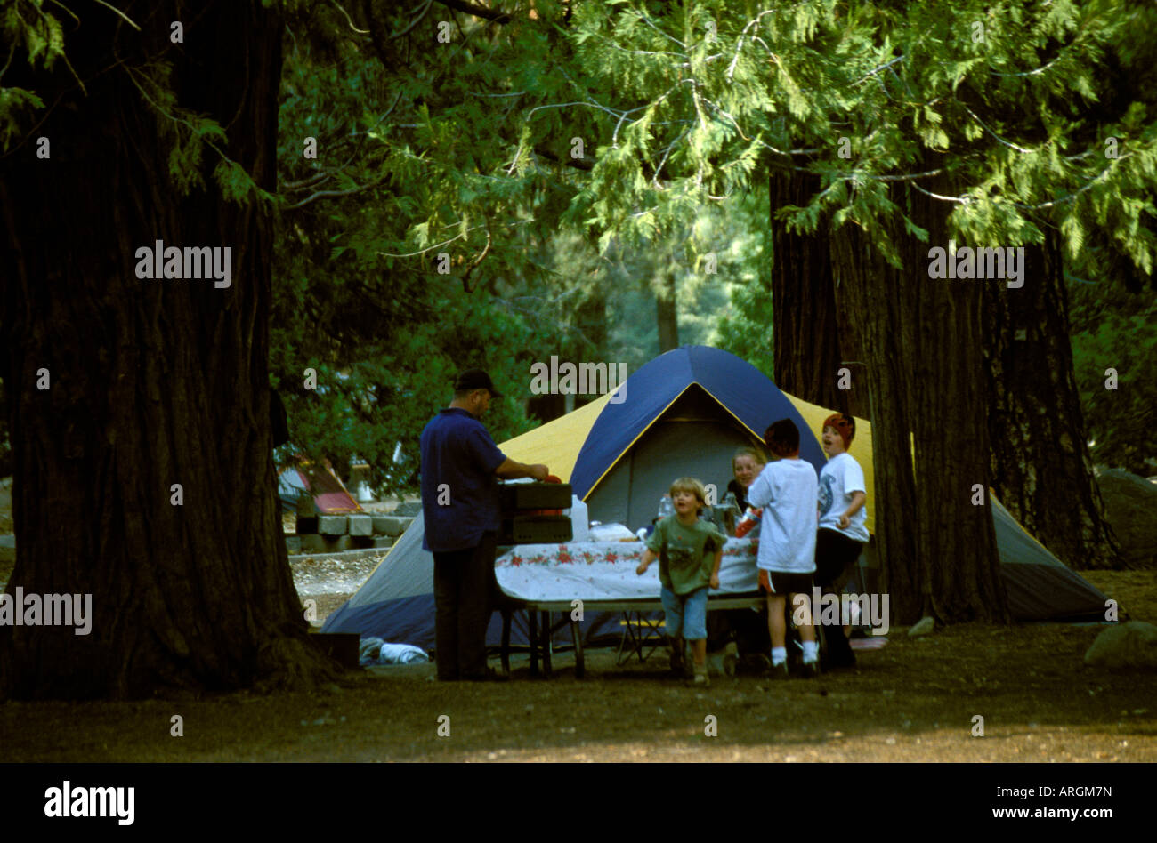 Eine Familie hat ein Zelt aufgeschlagen und bereitet ein Picknick auf einem Campingplatz im Yosemite-Nationalpark in Kalifornien. Stockfoto