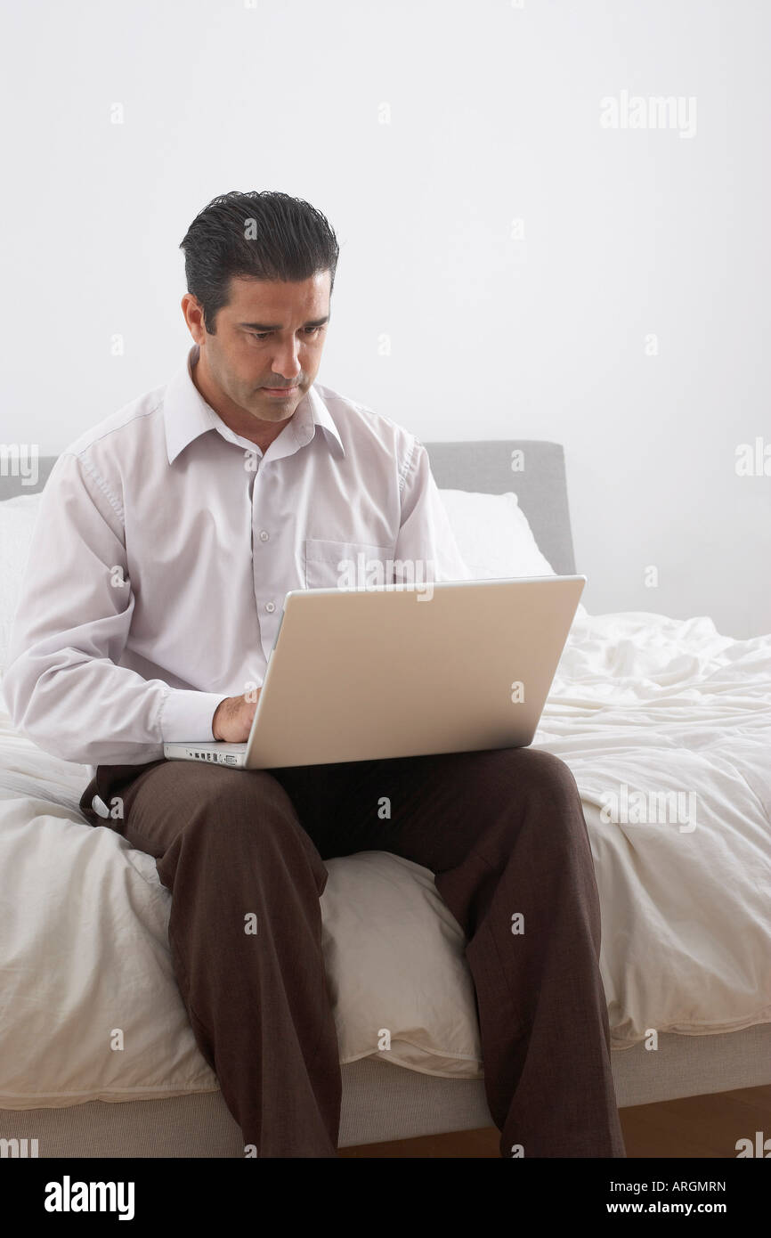 Mann mit Laptop am Bett Stockfoto