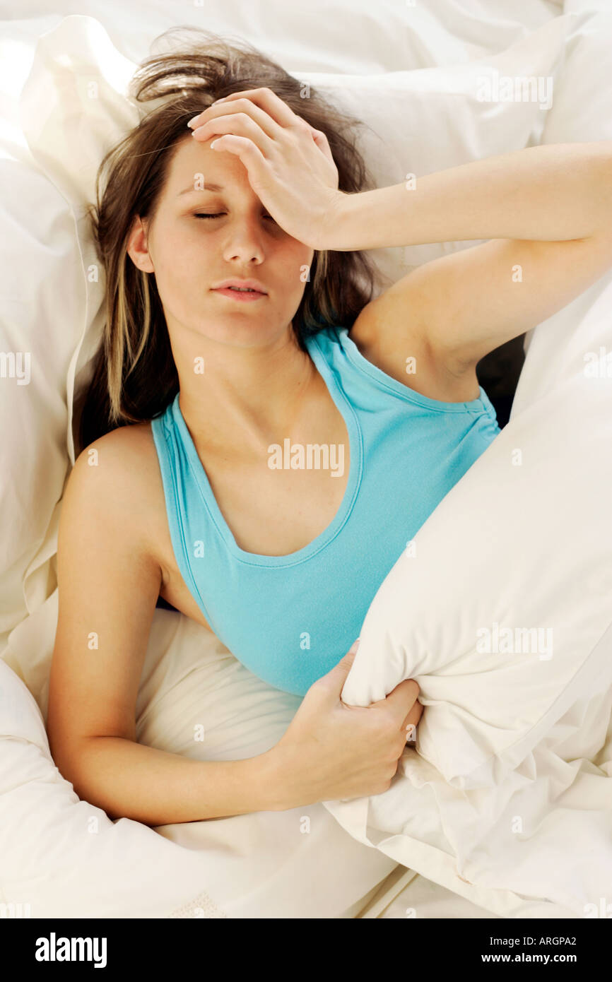 Mädchen im Bett mit Kopfschmerzen Stockfoto