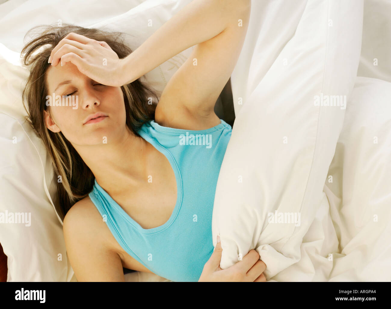 Mädchen im Bett mit Kopfschmerzen Stockfoto