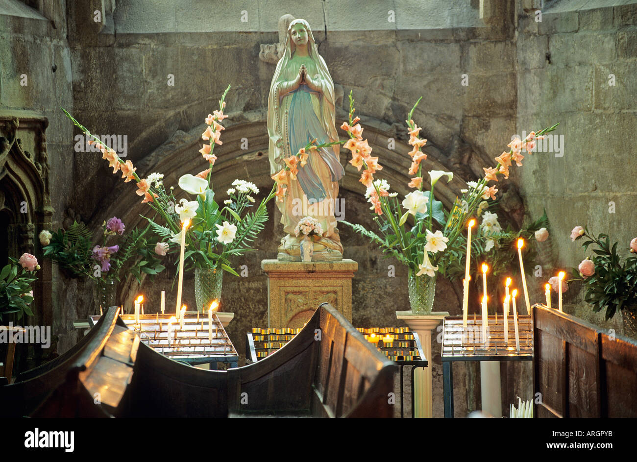Eine Alabaster Jungfrau steht umgeben von Kerzen und Blumen in das 12. Jahrhundert Basilika St Sauveur Stockfoto