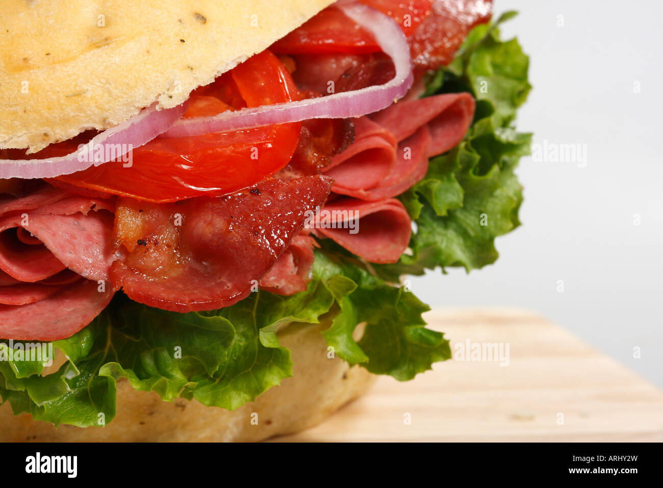 Ein Sandwich in Focaccia Bread, serviert mit gebratenem Speck auf dem Holzbrett Vorderansicht Niemand Nahaufnahme kreative Präsentation in den USA Hi-res Stockfoto
