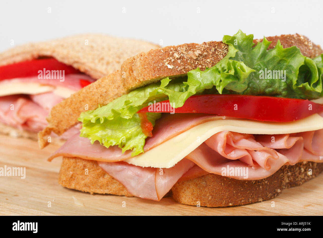 Nahaufnahme von Sandwiches ein Weißbrot mit Schinken Käse und Gemüse auf einem Holzbrett Vorderansicht horizontal niemand in den USA Hi-res Stockfoto