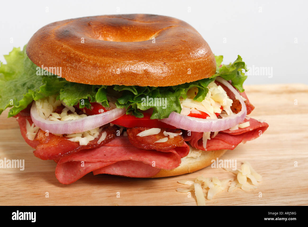Das Bagel-Sandwich auf weißem Hintergrund mit Salat auf einem Holzbrett isoliert ausgeschnitten Ausverkauf für auf Alamy horizontal in USA US hochauflösend Stockfoto