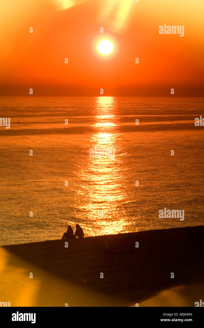 Ein paar beobachten den Sonnenuntergang über Brighton Beach erfasst durch die Linse der Sonnenbrille, Brighton, East Sussex, UK. Stockfoto
