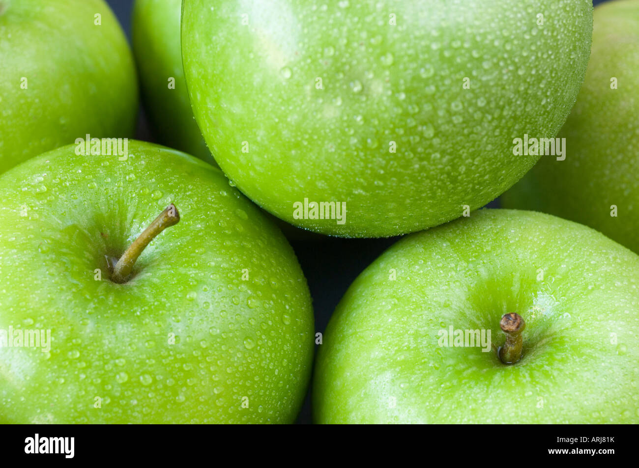 Frische grüne Bio-Äpfel, Stiele mit Tröpfchen Tau befestigt. Auf dem Display übereinander gestapelt Stockfoto