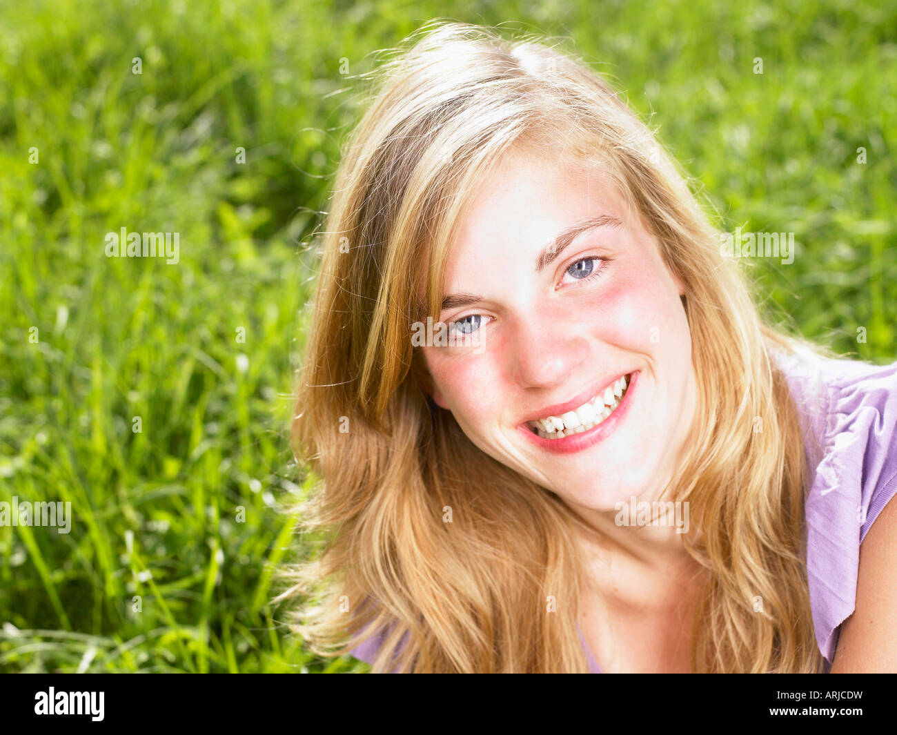 Junge Frau sitzt in einem Feld Stockfoto