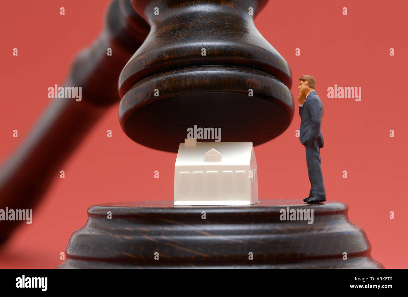 Symbolische Foto: Zwangsversteigerung - ein Haus und ein Mann unter einem Richter Hammer. Stockfoto