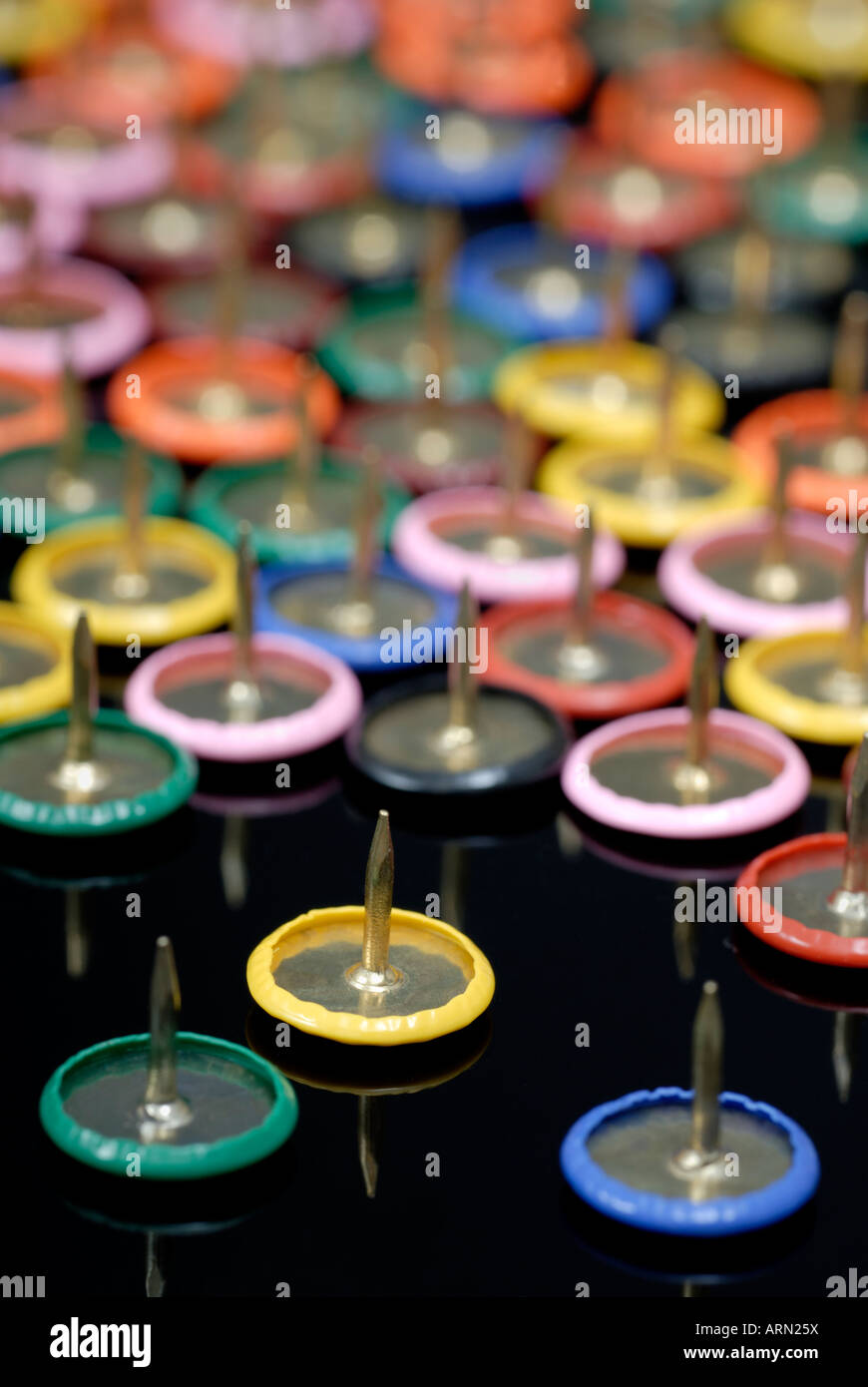Farbige Reißnägel auf schwarzem Hintergrund Stockfoto