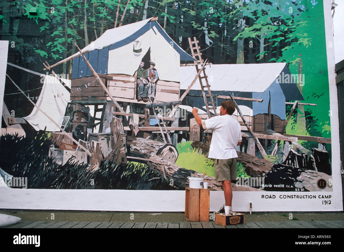 Künstler repariert sein Wandbild, Chemainus (Stadt der Wandmalereien), Vancouver Island, British Columbia, Kanada. Stockfoto