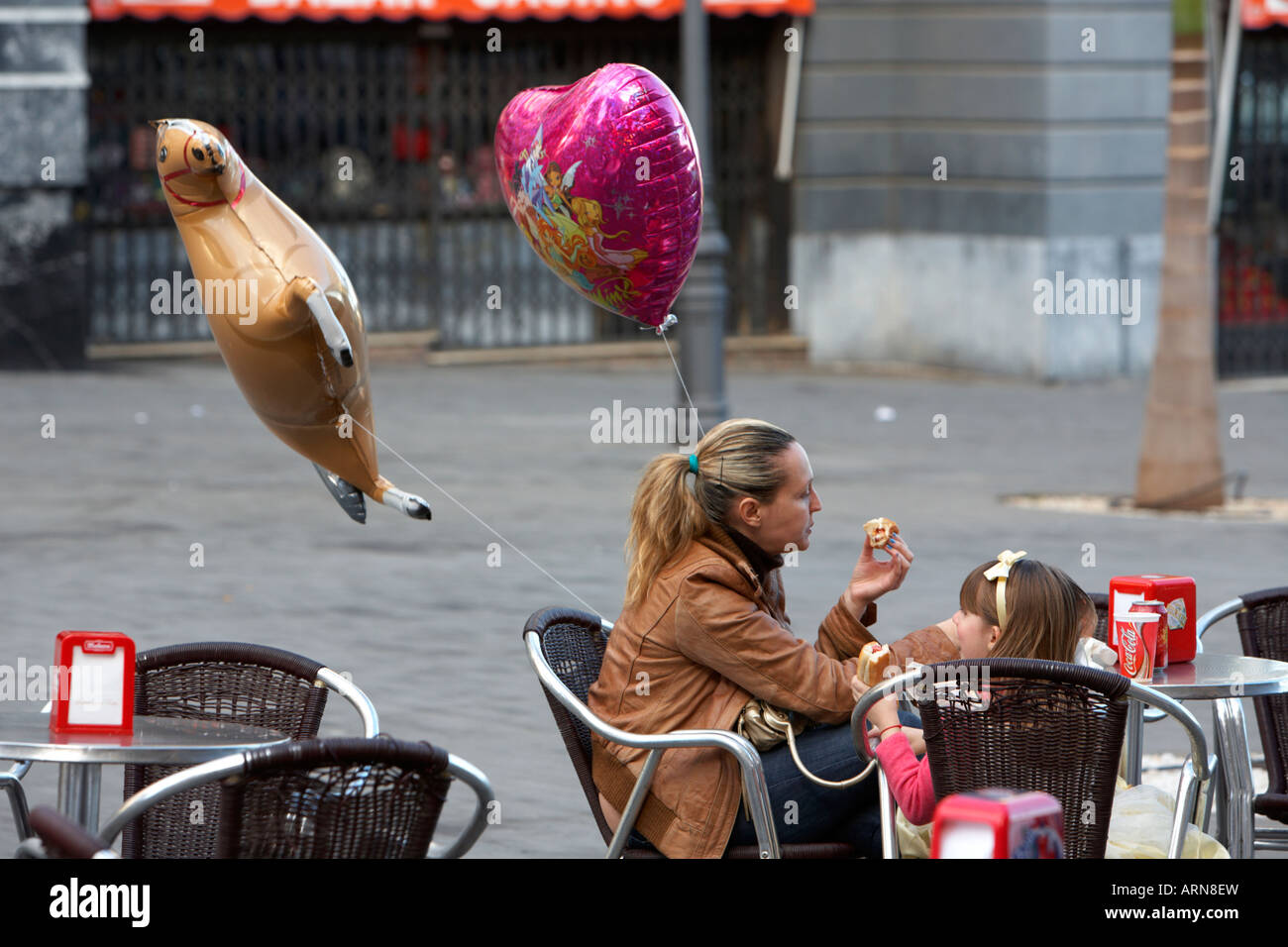 Mutter und Tochter sitzen in einem Straßencafé zu Mittag mit Helium gefüllte Ballons Carnaval Santa Cruz Teneriffa Kanarische Insel Stockfoto