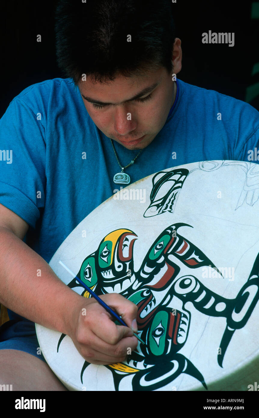 Erste Nationen Mann Farben Trommel in Kwakwaka'wakw (Kwakiutl) Tradition, Vancouver Island, British Columbia, Kanada. Stockfoto