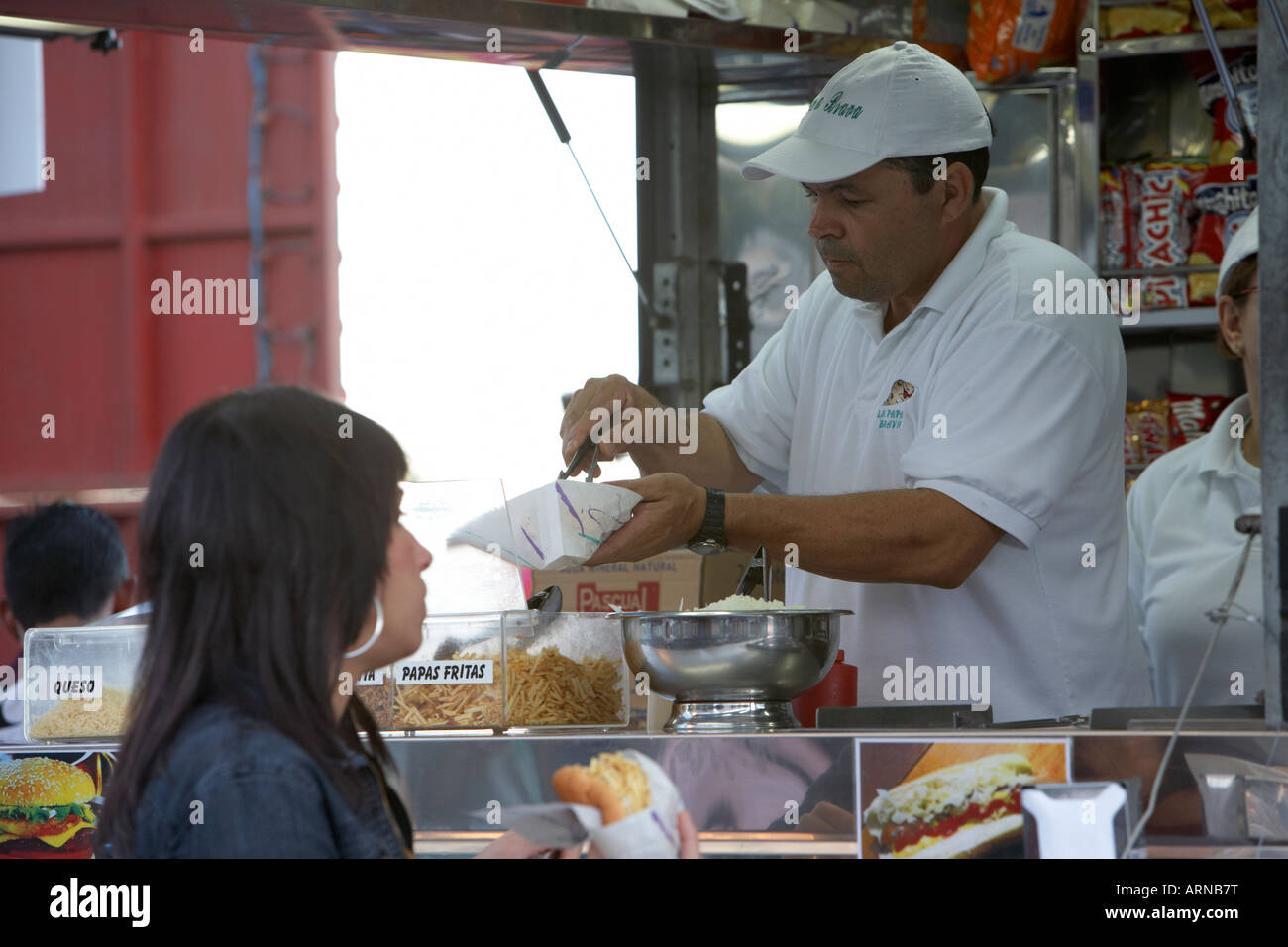 Stall-Betreiber machen Hotdogs vor Kundin am Fast-Food-Stand während Carnaval Zeit in Santa Cruz De tenerife Stockfoto