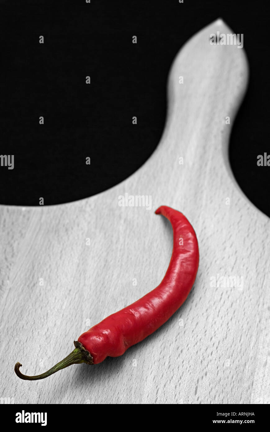 Farbausführung rote Chilischote auf ein Schneidbrett aus Holz gegen einen schwarzen Hintergrund Capsicum Annum Stockfoto
