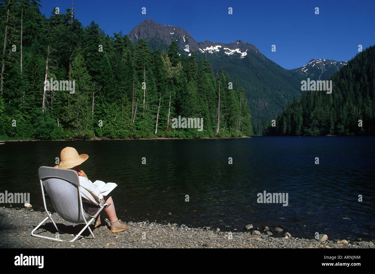 Schoen See mit älteren Frau liest am Ufer, Vancouver Island, British Columbia, Kanada. Stockfoto