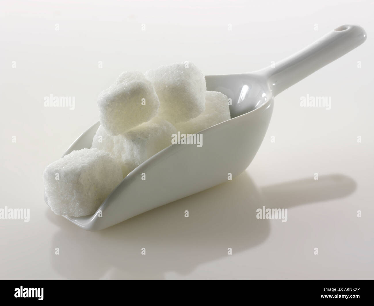 Grob geschnittene weiße raffinierte Zuckerwürfel noch Leben gegen ein Weißer Hintergrund Stockfoto