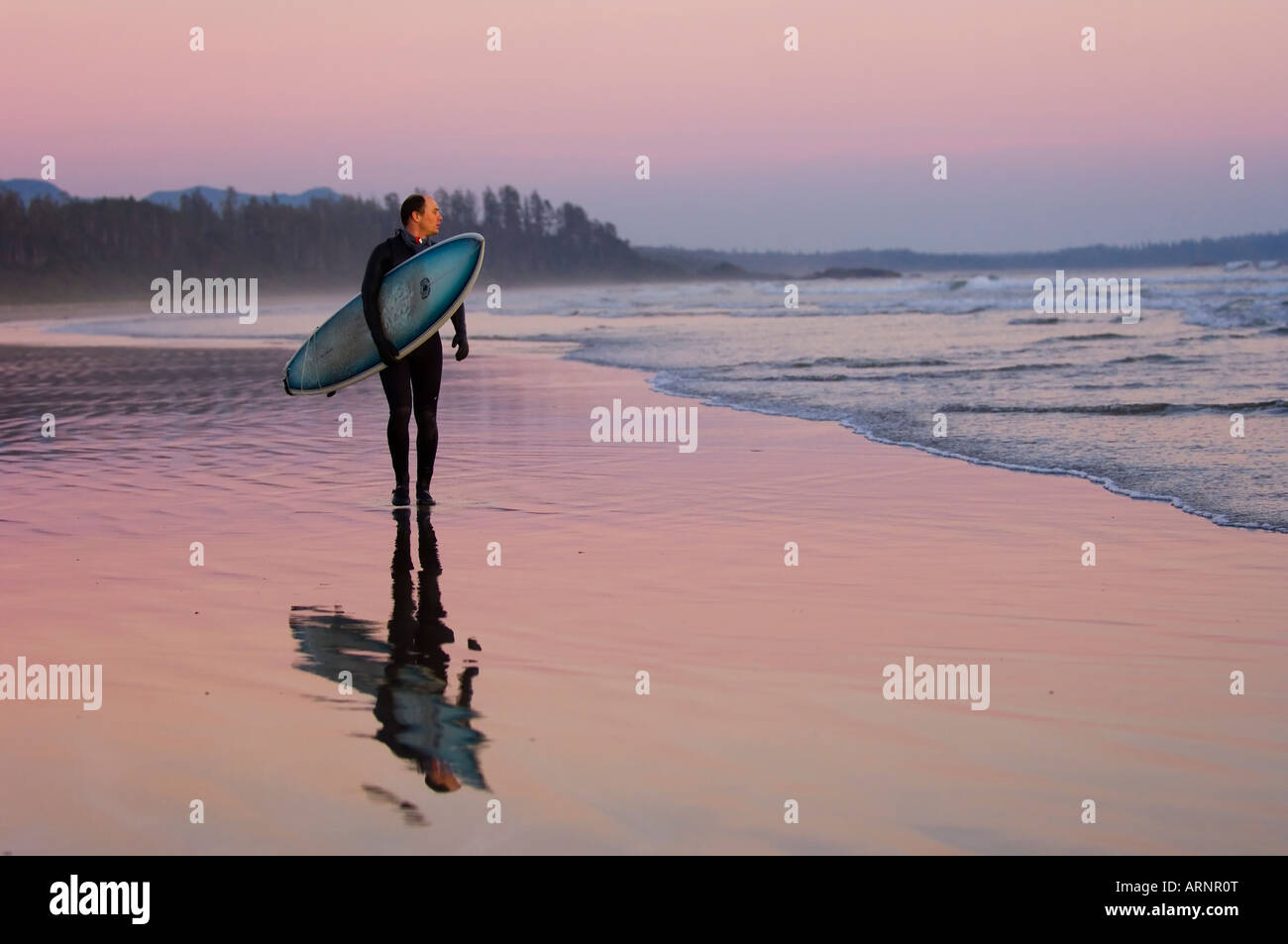 Surfer geht Küstenlinie, Pacific Rim National Park, Long Beach, Vancouver Island, British Columbia, Kanada. Stockfoto